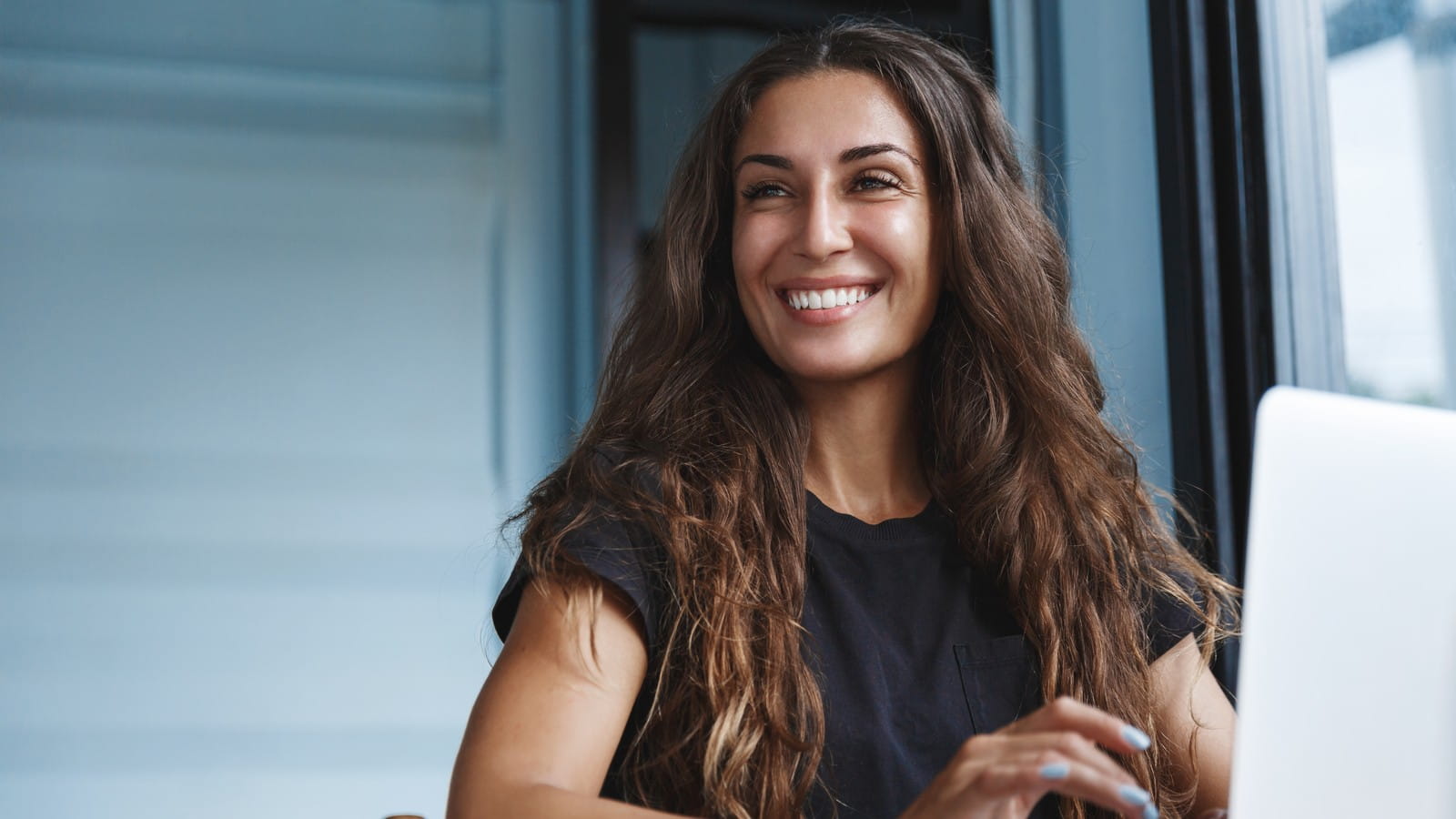 A smiling woman sitting at a desk with a laptop