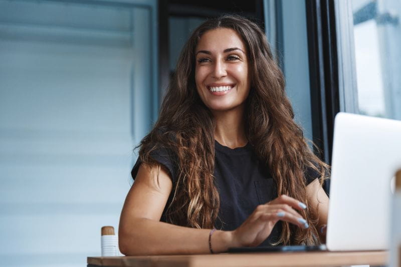 A smiling woman sitting at a desk with a laptop