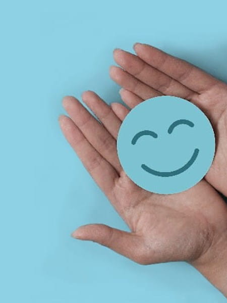 Hands holding a blue circle with a smiling face on it