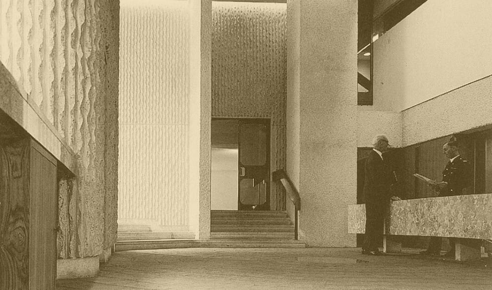 a black and white picture of the lobby of a modernist building with concrete walls