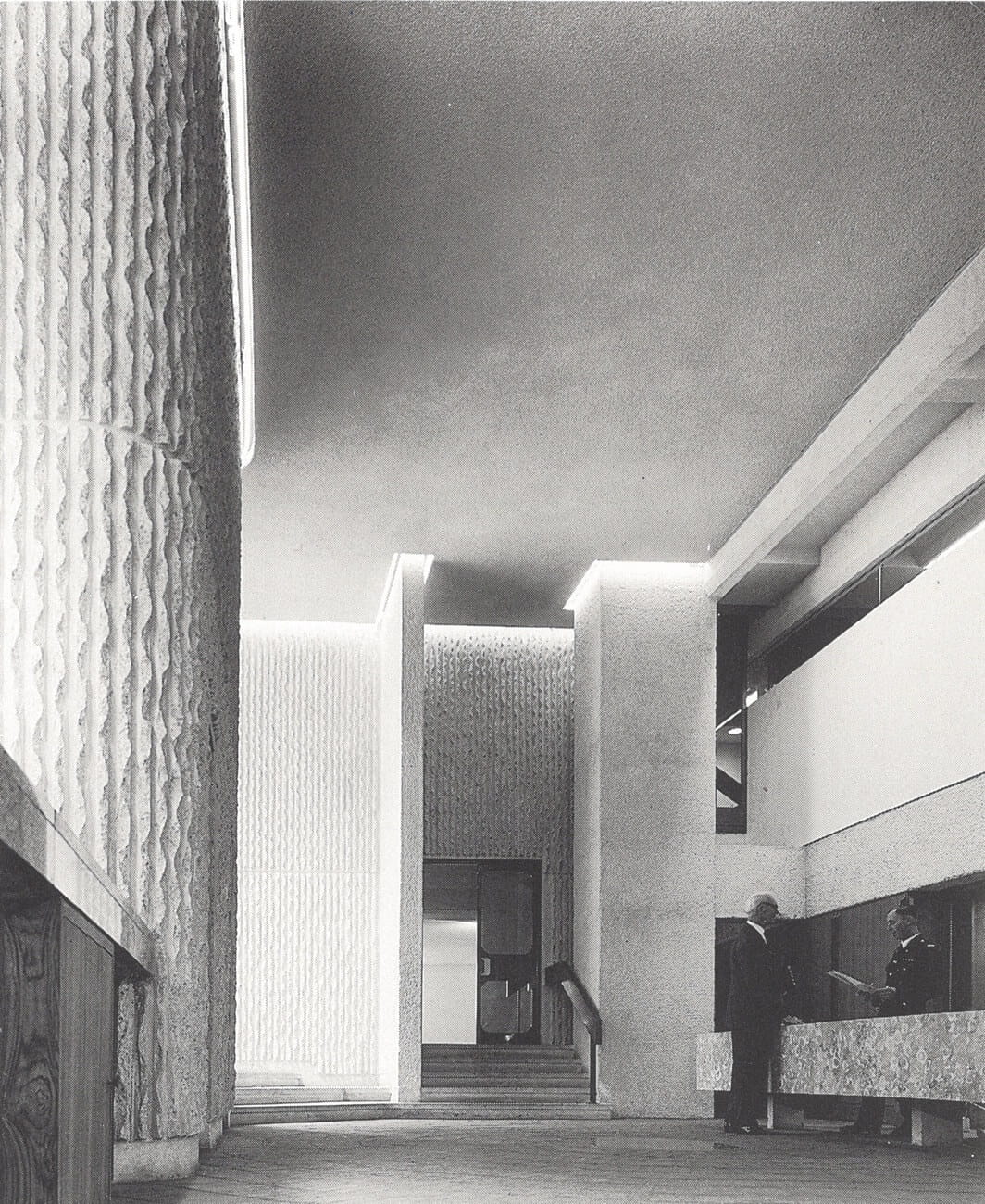 a black and white picture of the lobby of a modernist building with concrete walls