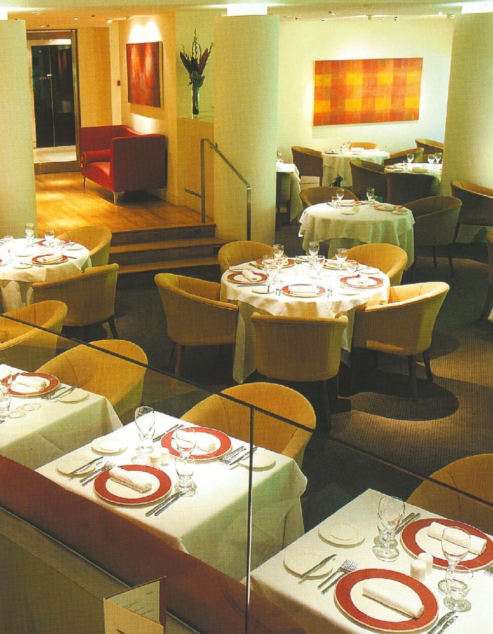 picture of an empty restaurant with tables set and art work on the walls