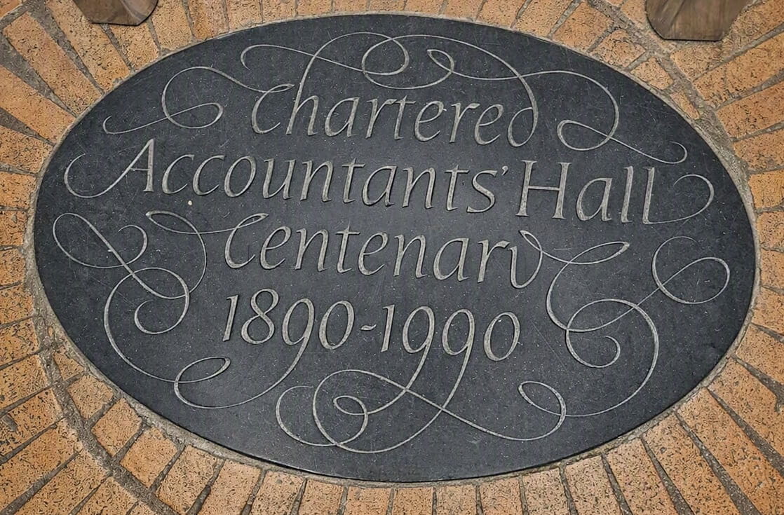 Picture of an engraved marble floor plaque, surrounded by terracotta floor tiles