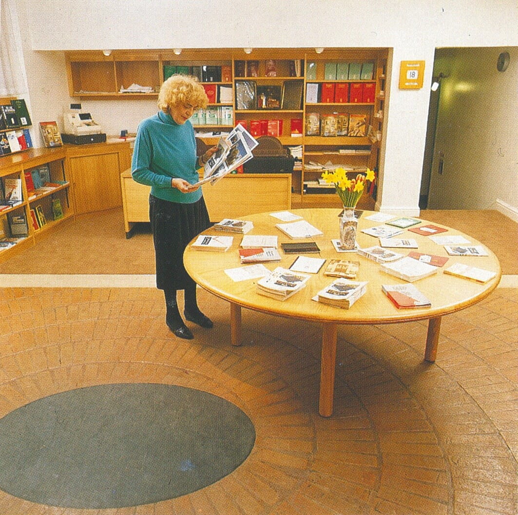 a photograph of a woman looking at some books on a table in a shop