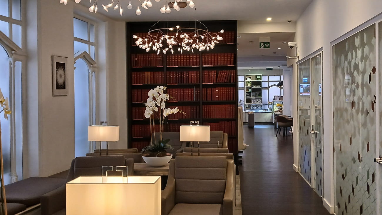 A bookshelf  full of leather bound books at the end of a business lounge