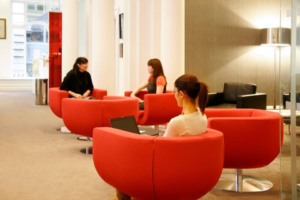 people sitting in red chairs in a business lounge