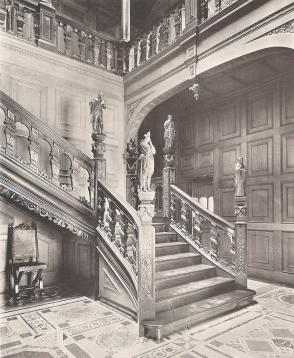 A black and white photograph of an ornate hallway and stairs
