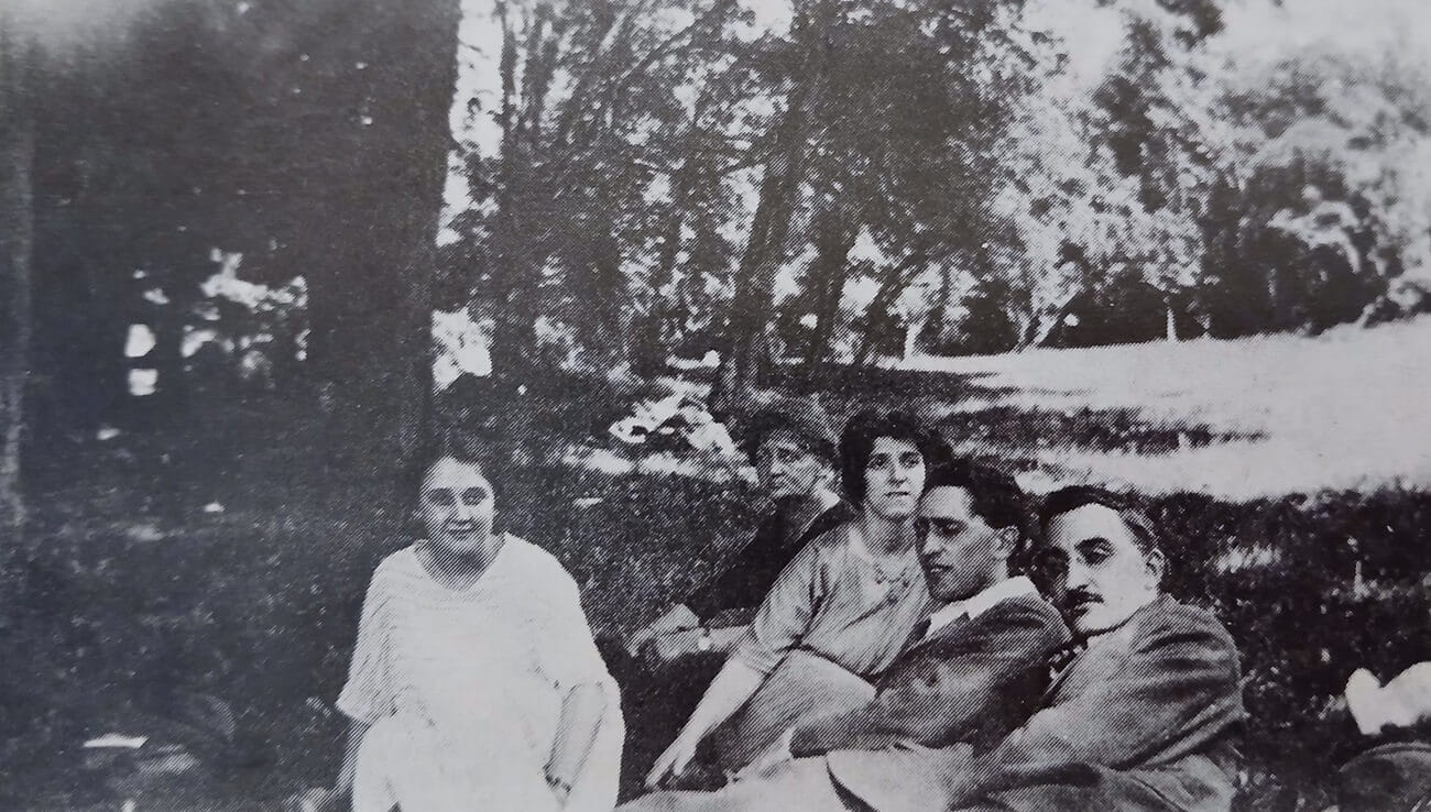 A vintage black and white headshot of a group of people in a park in the 1920s