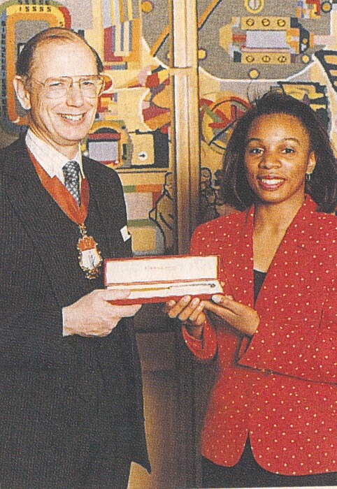 A photograph of a woman being presented with a prize