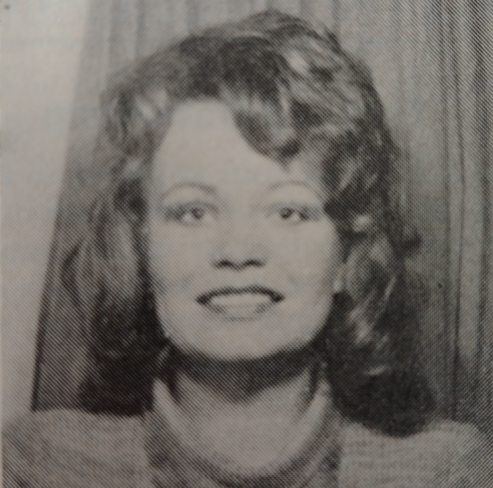 A vintage photograph of a smiling young woman taken in a photobooth