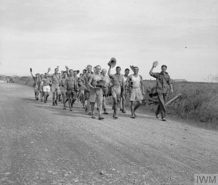 black and white vintage photo of world war Allied prisoners of war walking down a road in Thailand