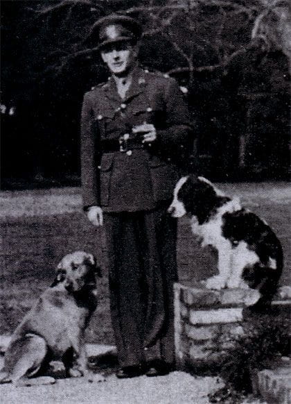 Vintage black and white photo of a man in military uniform with 2 dogs