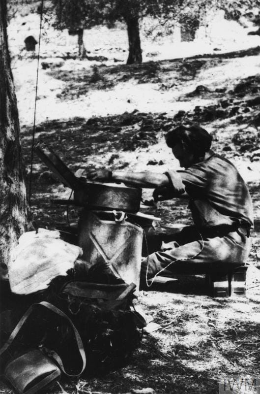 Special Operations Executive in Albania 1943-44. Radio operator Corporal Davis with B2 suitcase wireless set (resting on gerry cans) at Mukaj, August 1944.