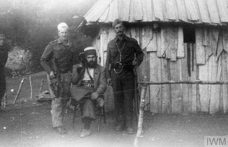 Special Operations Executive in Albania 1943-1944. Capt David Smiley, Baba Faja and Kadri Hoxha photographed in front of the wooden HQ building at Bixha, October 1943. (c)  IWM