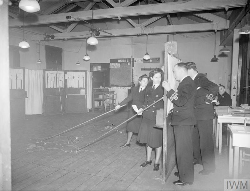 The Western Approaches Tactical Unit, where the problems of the anti U-boat warfare are fought out. 18 March 1945, Derby House. Viewgiving through peepholes. Course Officers are examining the situation as they do at each move, through peepholes. © IWM (A 27819)