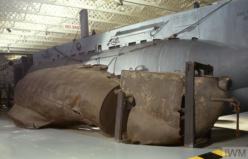 A photograph of the remains of a midget submarine with a complete, larger submarine behind