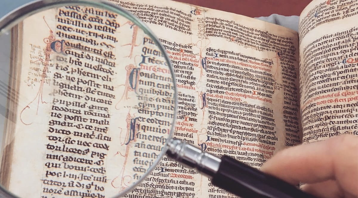 Magnifying glass enlarging some Latin text in old book