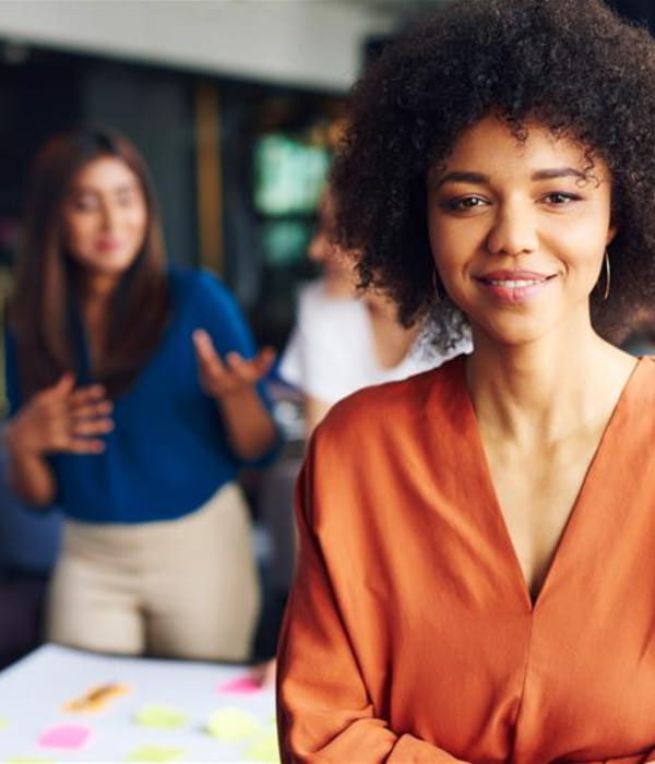 Image of smiling woman with colleagues chatting behind her