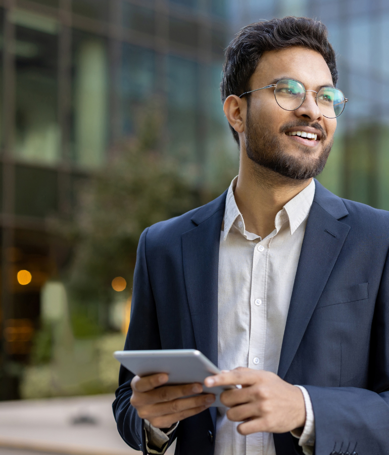 Young businessman outside an office building, holding a tablet.