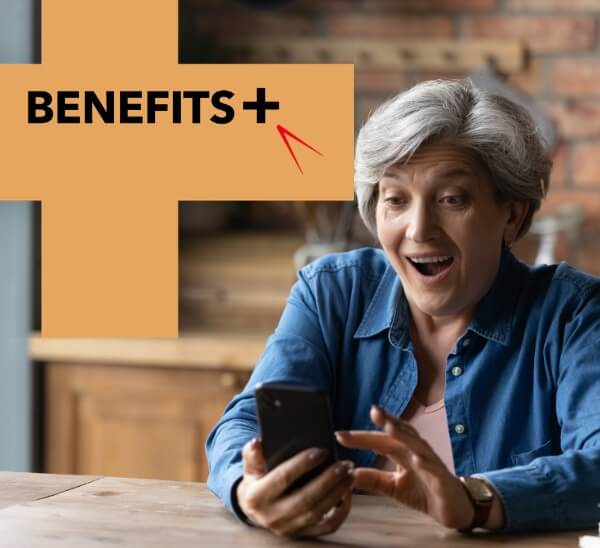 Benefits plus more from your membership. A woman in a home setting looking at a mobile phone, with a pleased expression