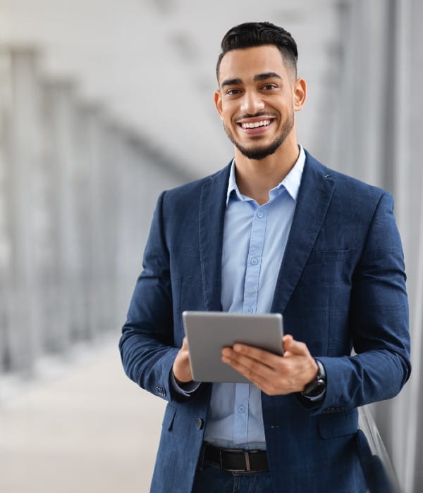 Young businessman outside an office building, holding a tablet.