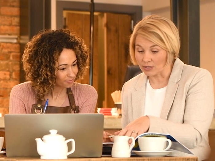 Two women working over a coffee