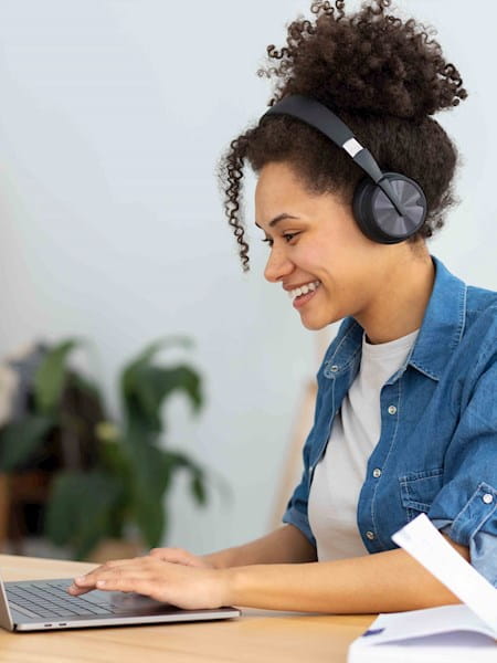 Woman with laptop open and headphones. 
