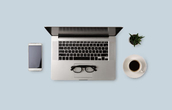 Mobile phone, laptop and glasses with a coffee cup on a blue background.