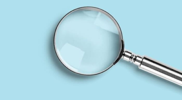 Silver magnifying glass on a purple background