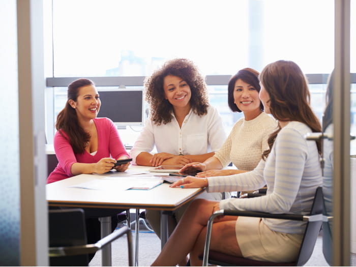 A group of 4 females talking to each other in a meeting