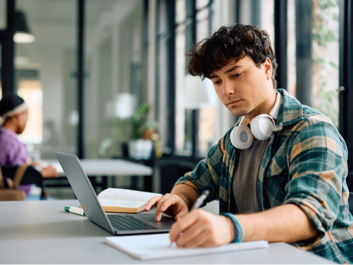 Man wearing headphones around his neck, working on his laptop