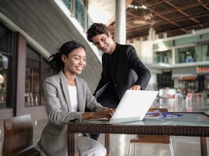 Two people working near laptop