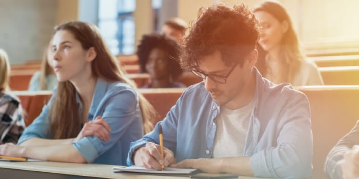 Male student taking notes during a lecture