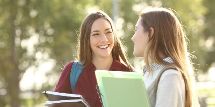 Two young female students talking to each other