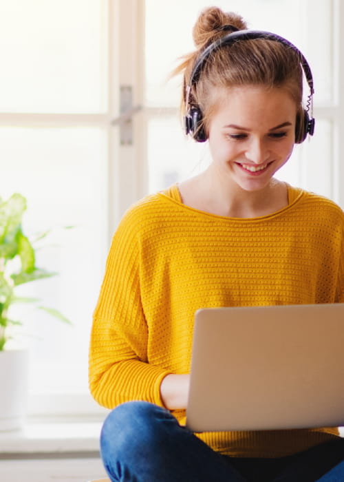 Young woman in a yellow top working on a laptop