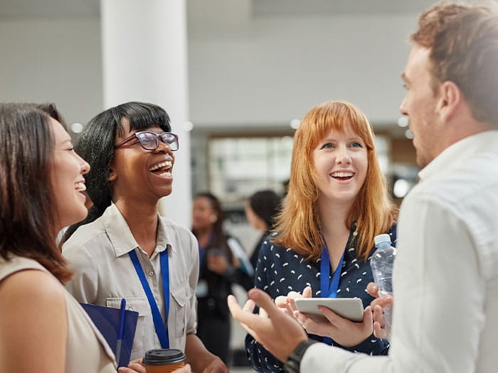students standing in a group laughing talking lanyards ID London Student Society