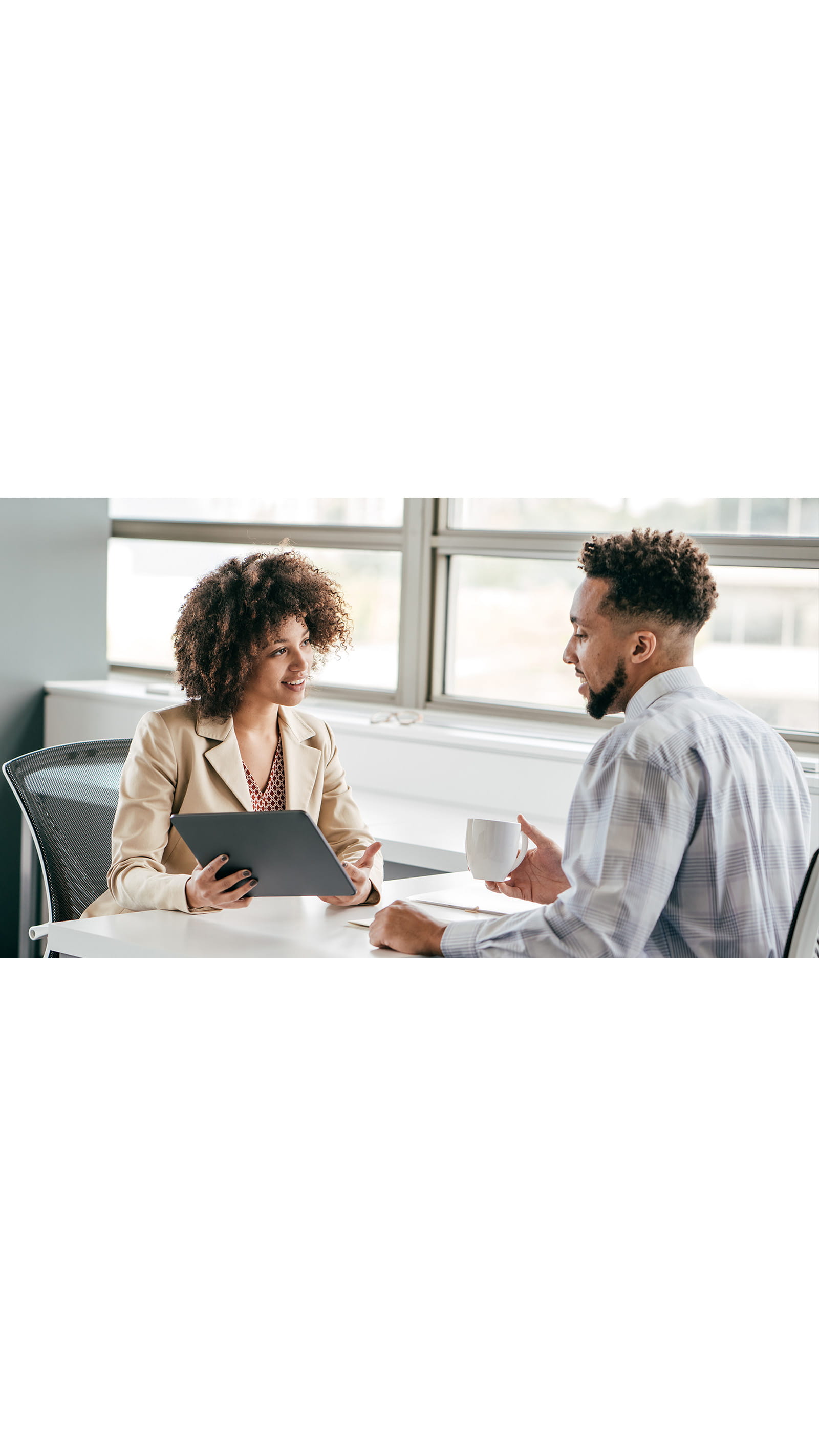 two colleagues coworkers office meeting room young woman afro natural curly hair young man coffee tablet windows