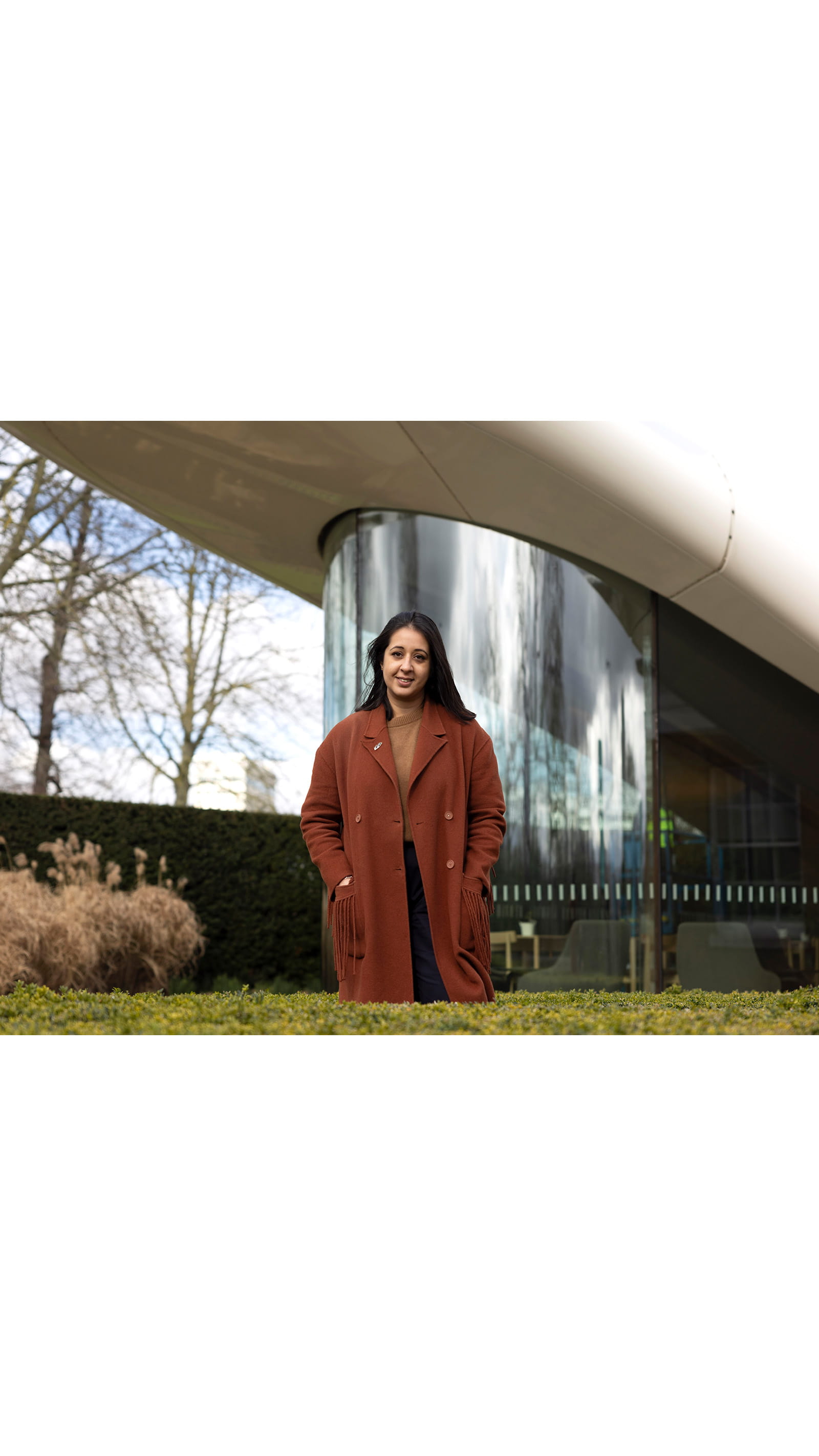 Alina Cummins, Head of Finance at Serpentine, young woman standing in front of modern glass building plants trees
