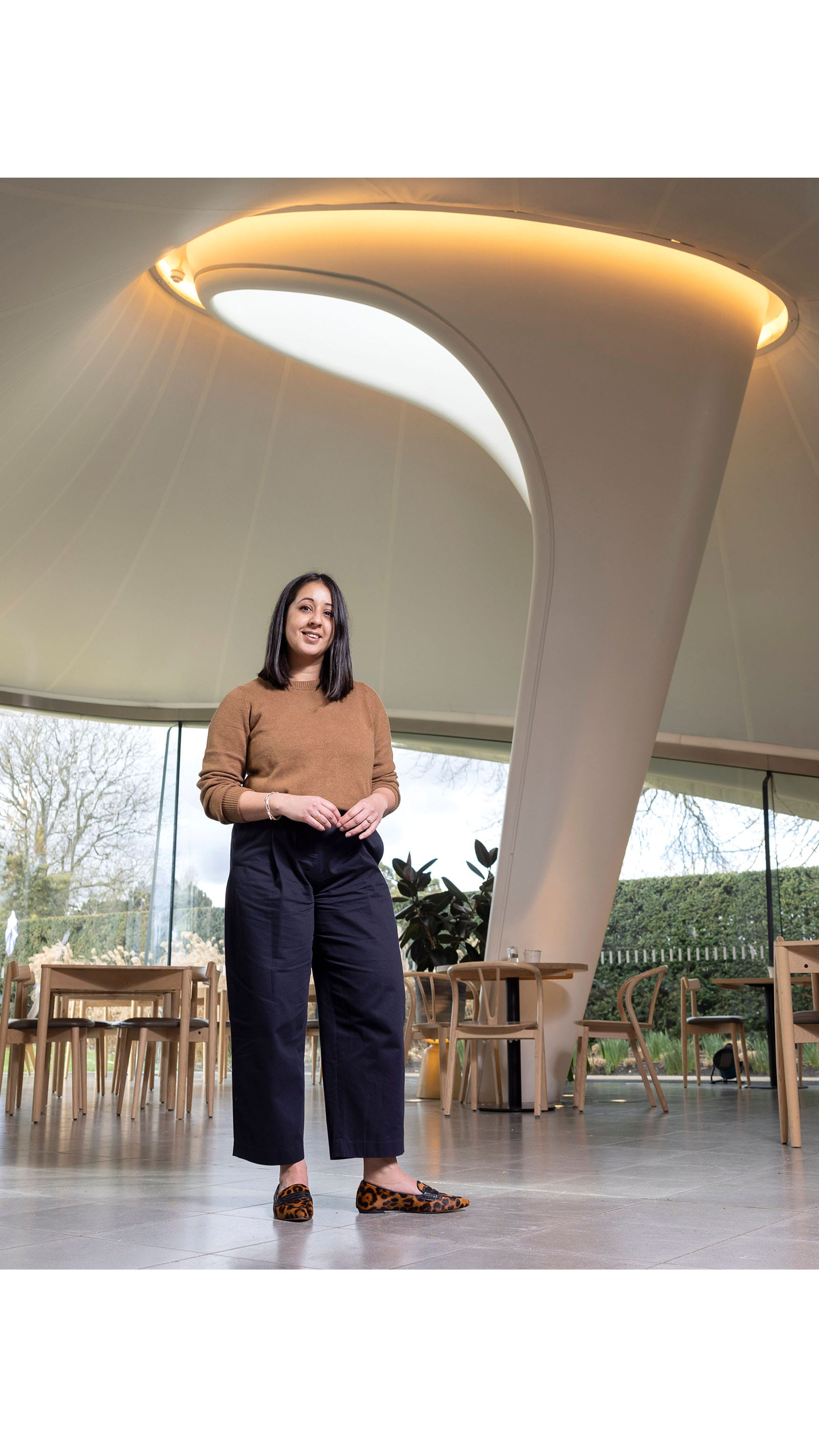 Alina Cummins, Head of Finance at Serpentine, young woman standing inside a modern building curved column glass windows