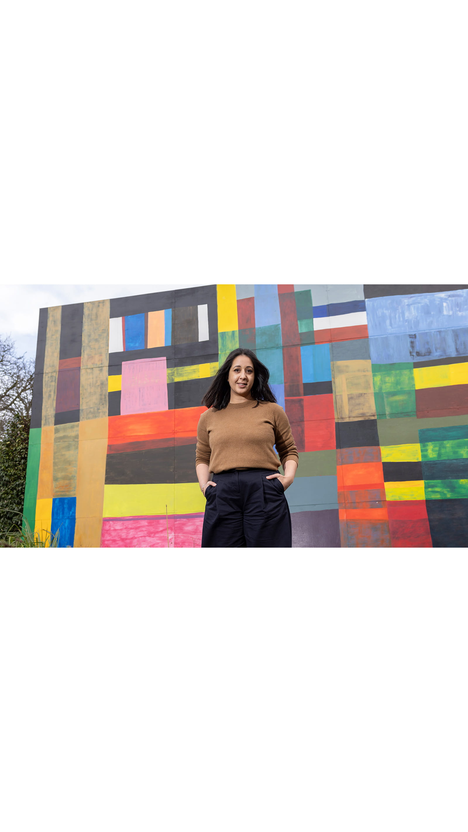 Alina Cummins, Head of Finance at Serpentine, young woman standing in front of wall mural colourful