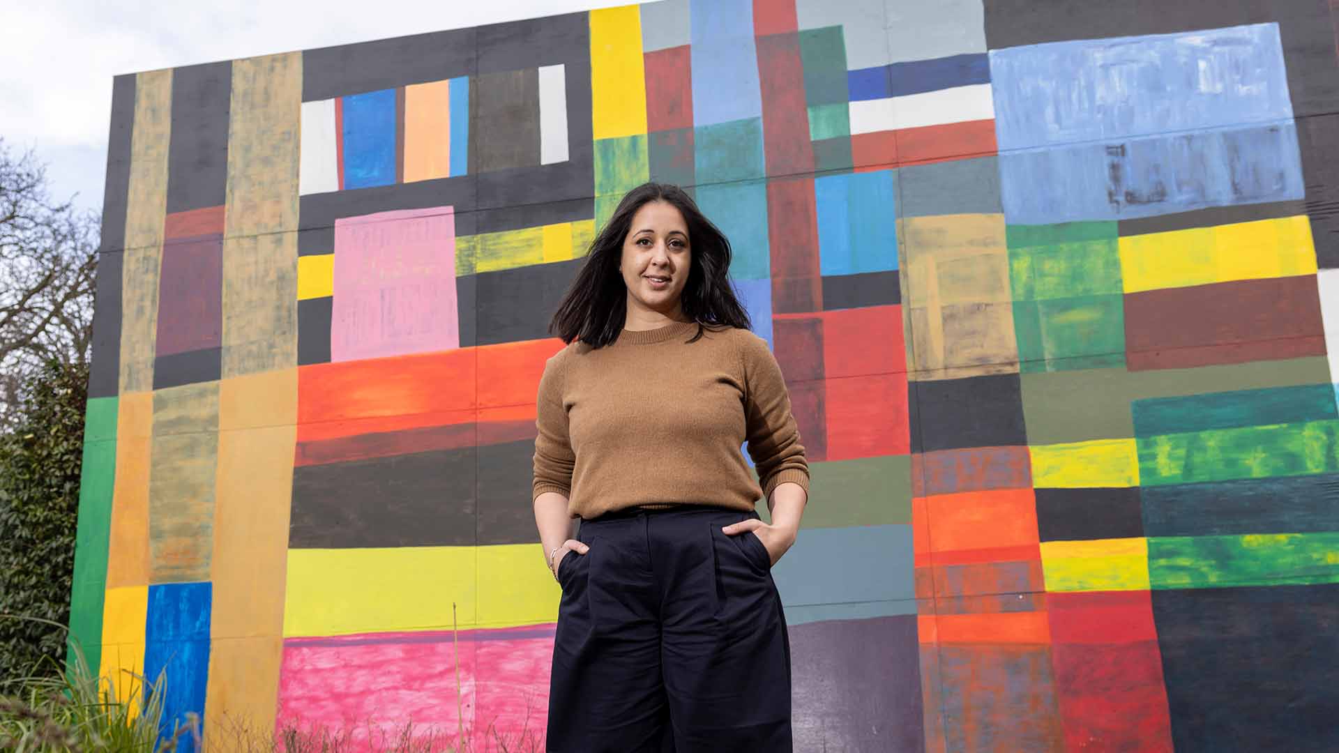 Alina Cummins, Head of Finance at Serpentine, young woman standing in front of wall mural colourful