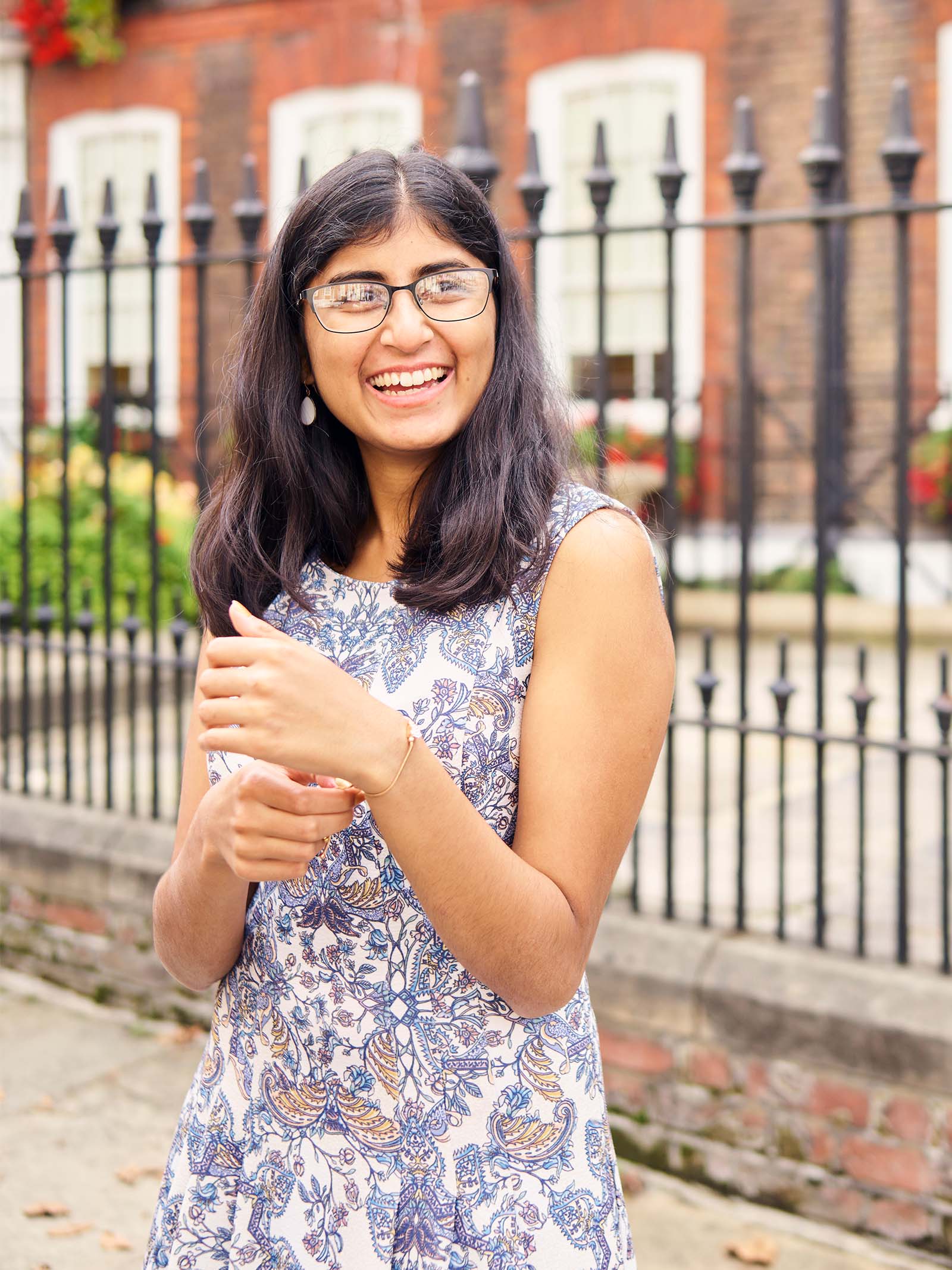 Audit trainee and ACA student Ashwini Poopalasingham standing in front of brick building and black iron fence, London city, UK