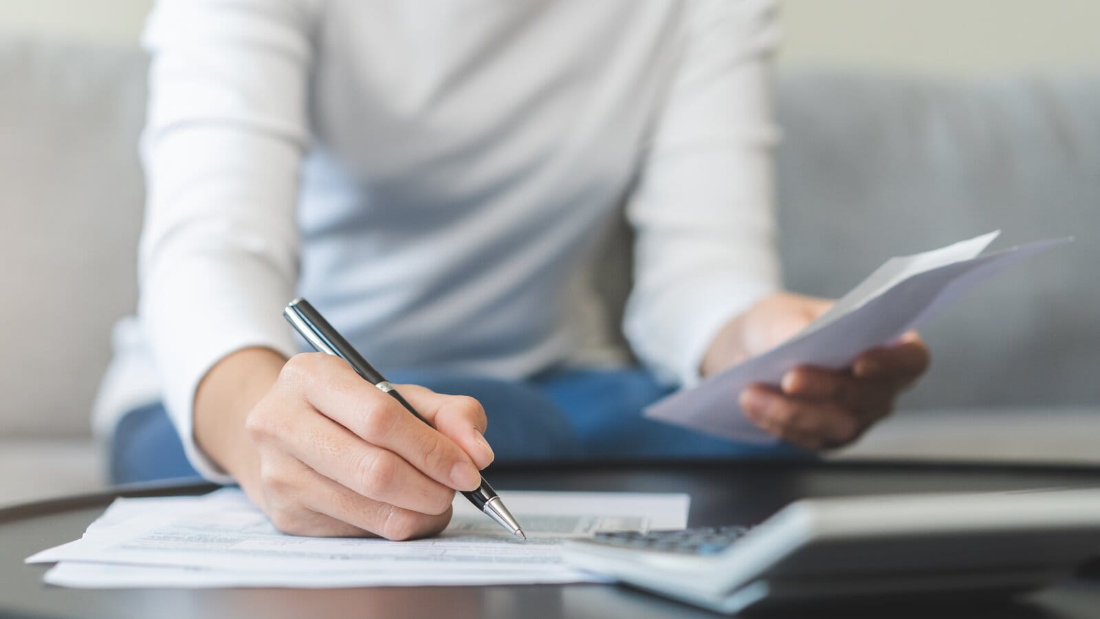 Person working on paperwork with a calculator