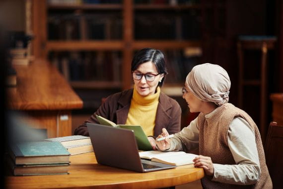 Female professor working with female student in a library