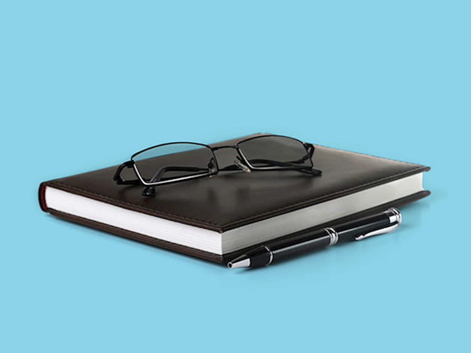 A notebook, pen and pair of glasses