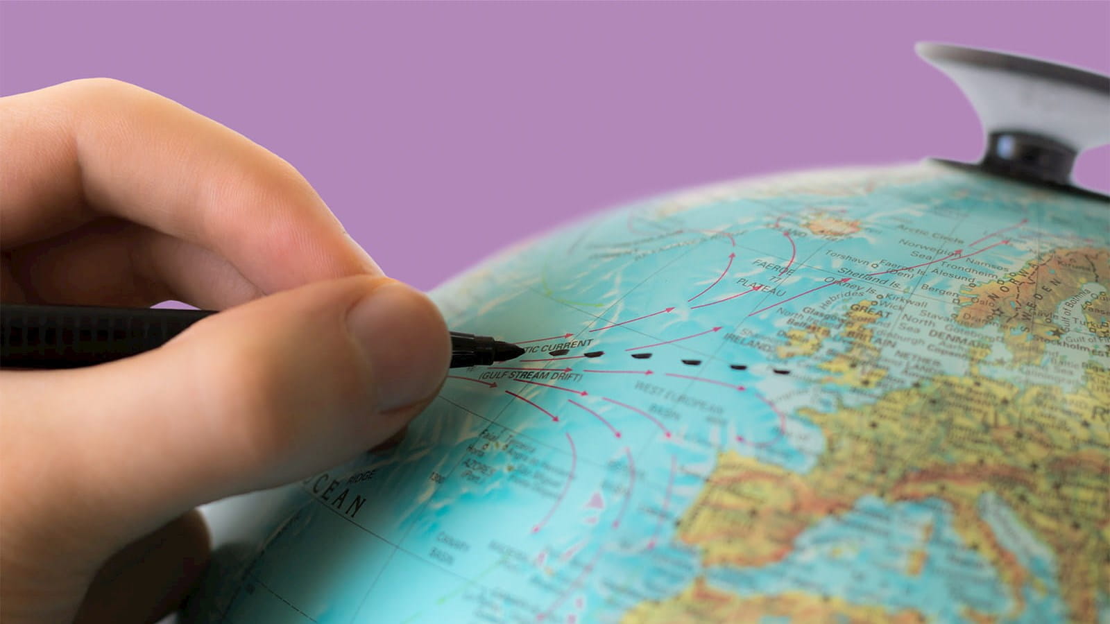 Hand drawing lines dots on the globe with a black permanant marker purple background