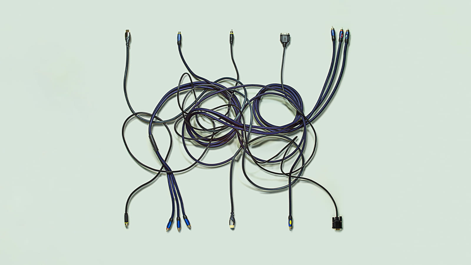 black electric cables in a mess entangled on a green background