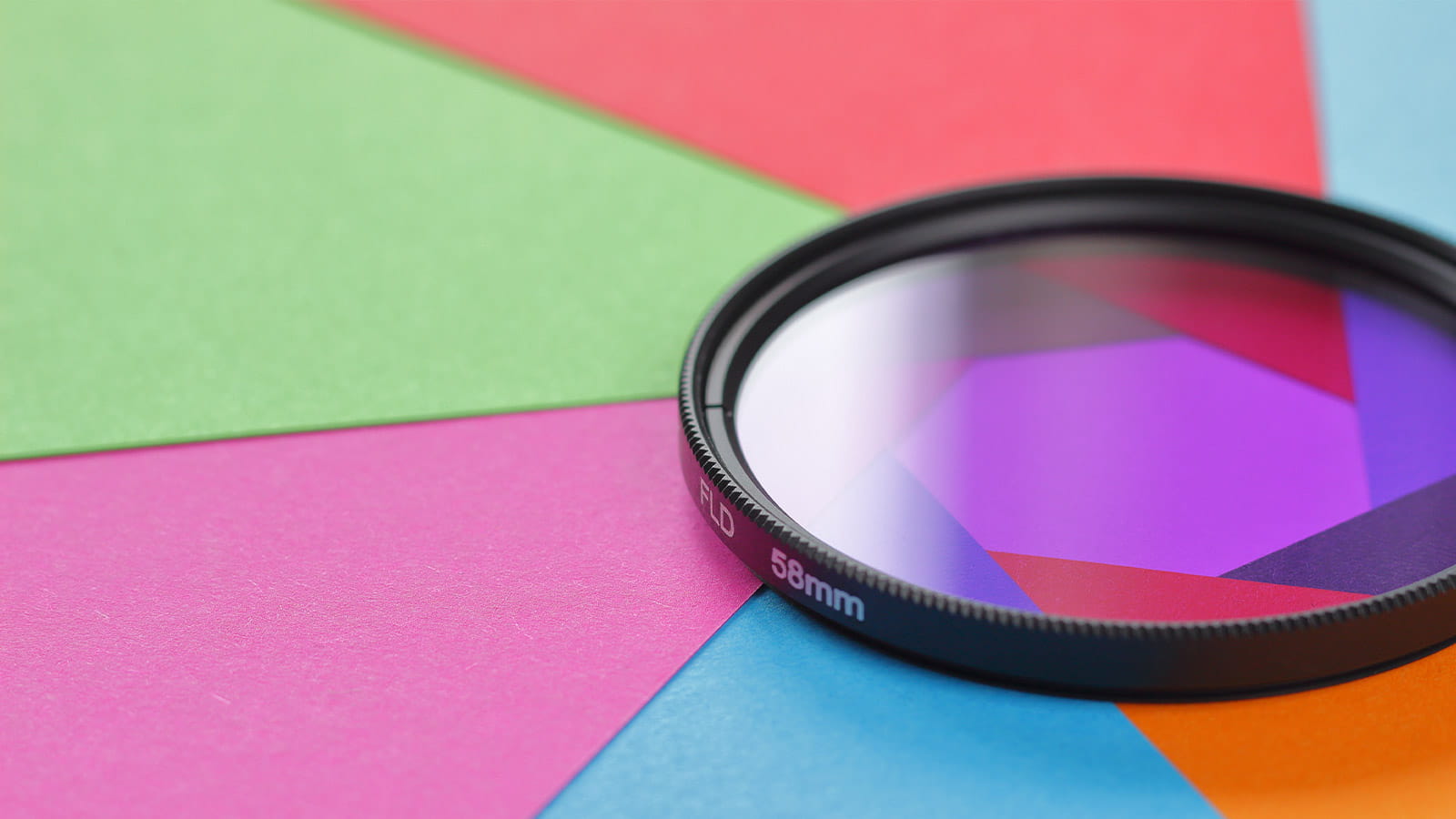 purple camera lens sitting on different coloured cards paper green red blue orange pink