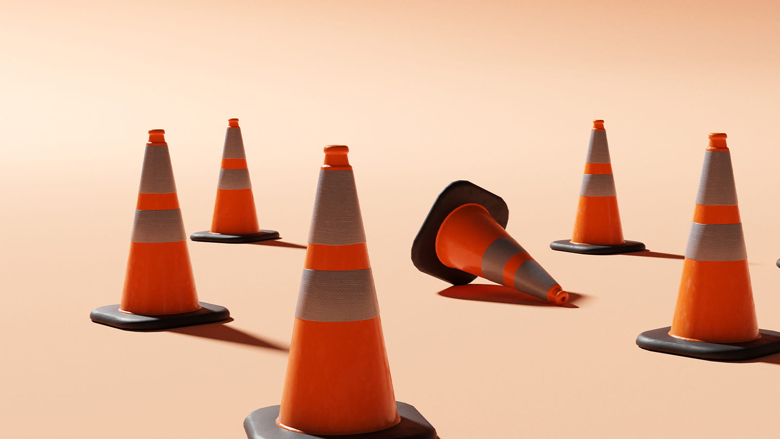 orange traffic cones standing in a group with one knocked over on its side