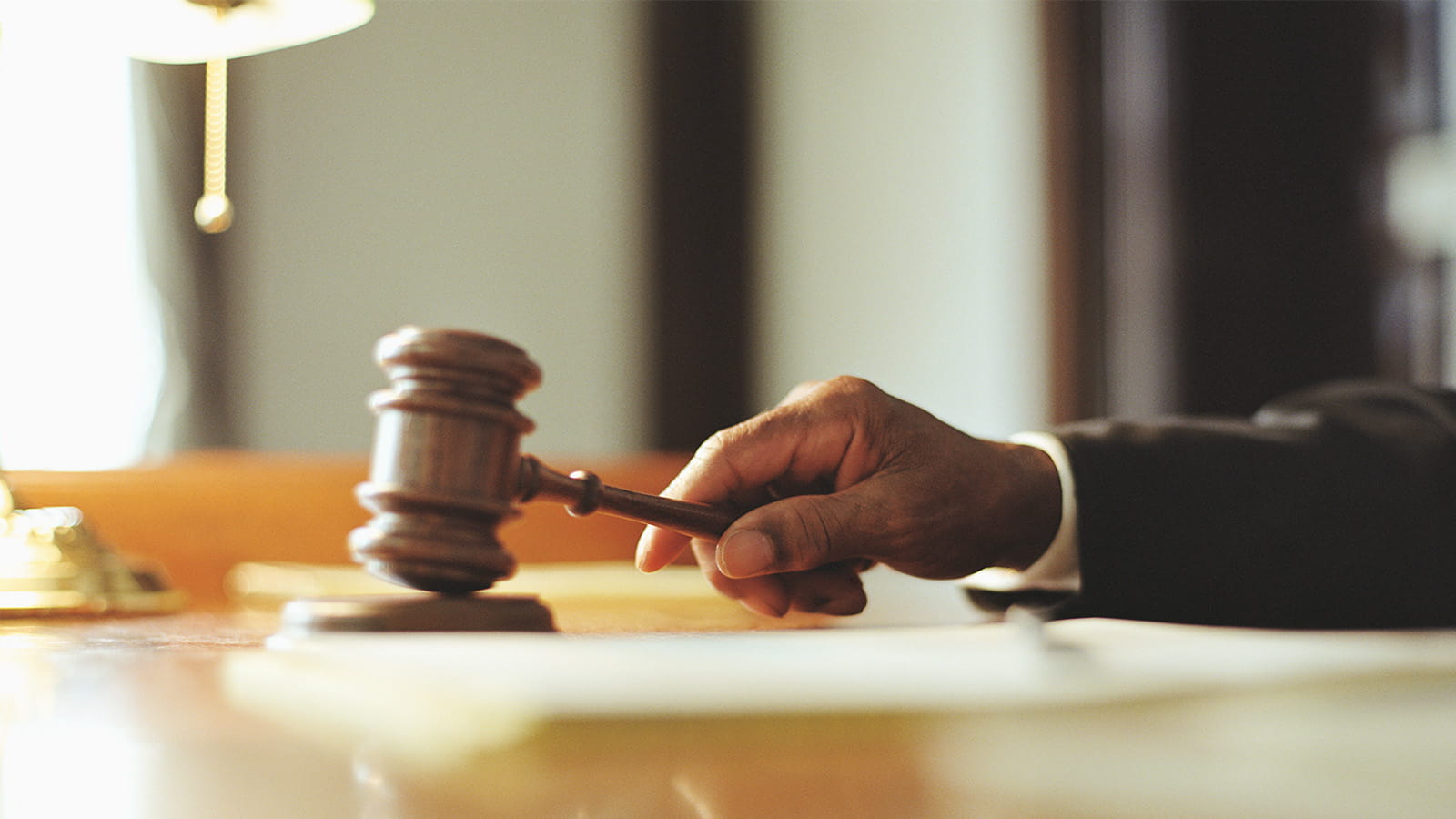hand judge holding a wooden anvil hammer courtroom law rules